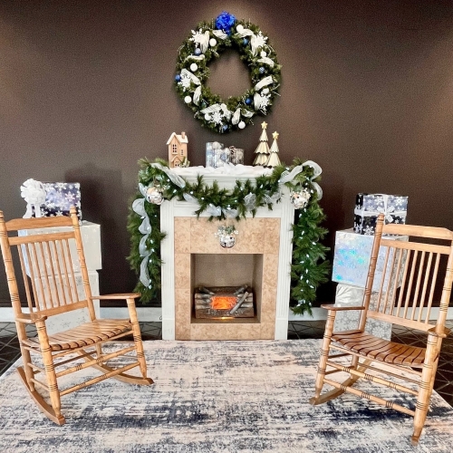 Cozy fireplace setup at ROA with a wreath, rug, and two chairs