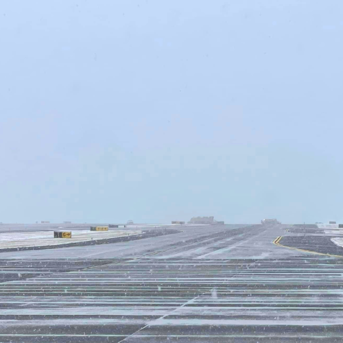 Snow covered airfield at ROA with plow vehicles in background