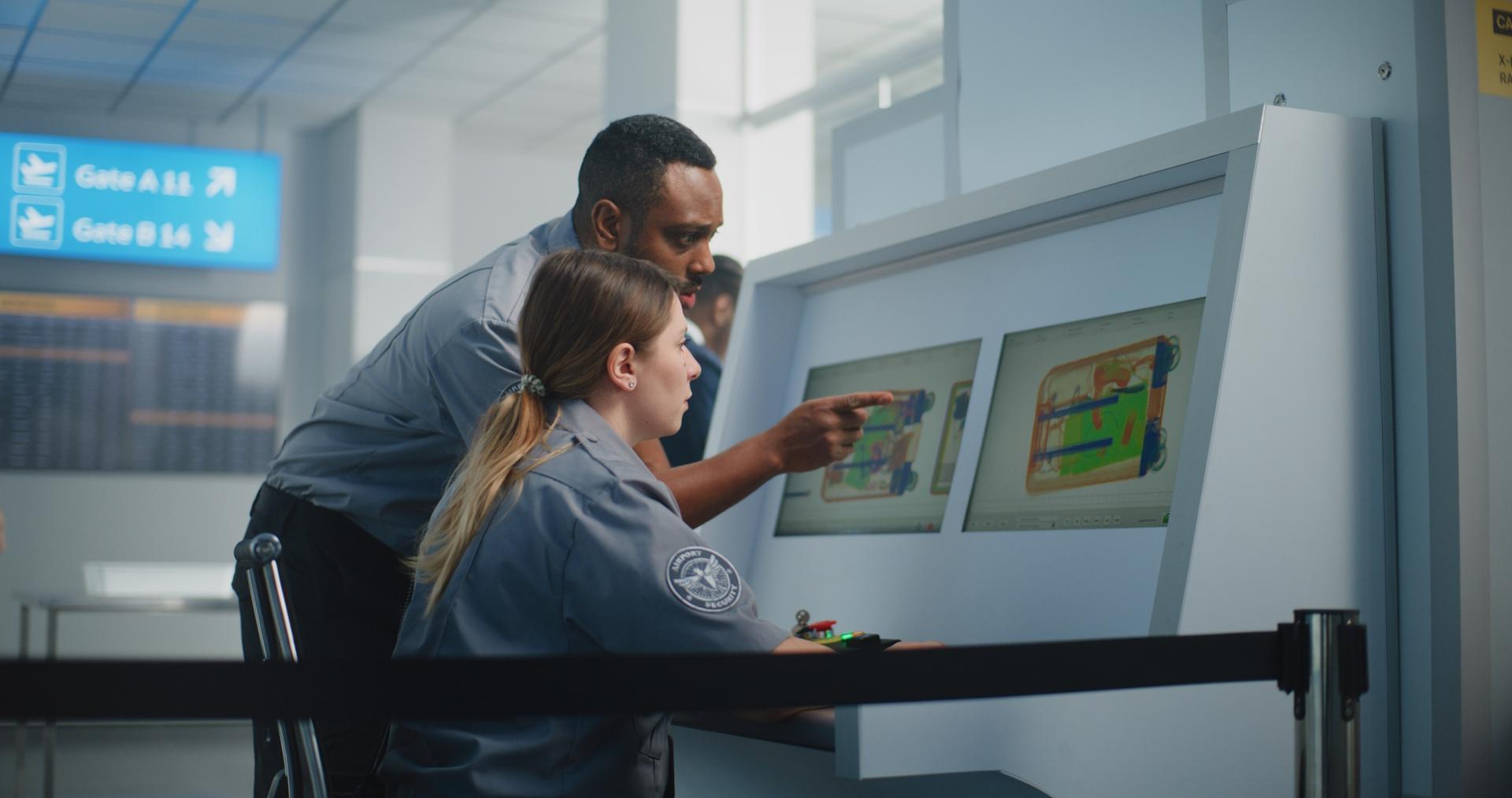 Two security personnel looking at a large computer screen