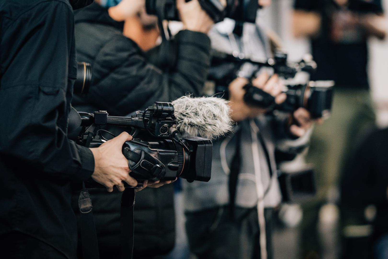 A closeup of multiple people holding cameras