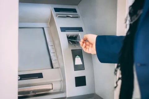 A person putting a card into an ATM