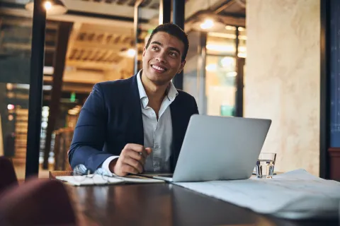 A man seated at a table with a laptop in front of him