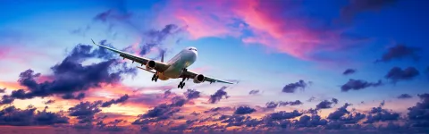 A large airplane flying through the air with clouds in the background