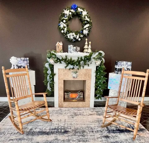 Cozy fireplace setup at ROA with a wreath, rug, and two chairs