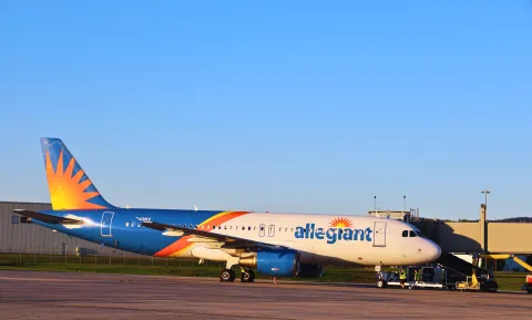 Allegiant plane parked at ROA gate on a blue sky day